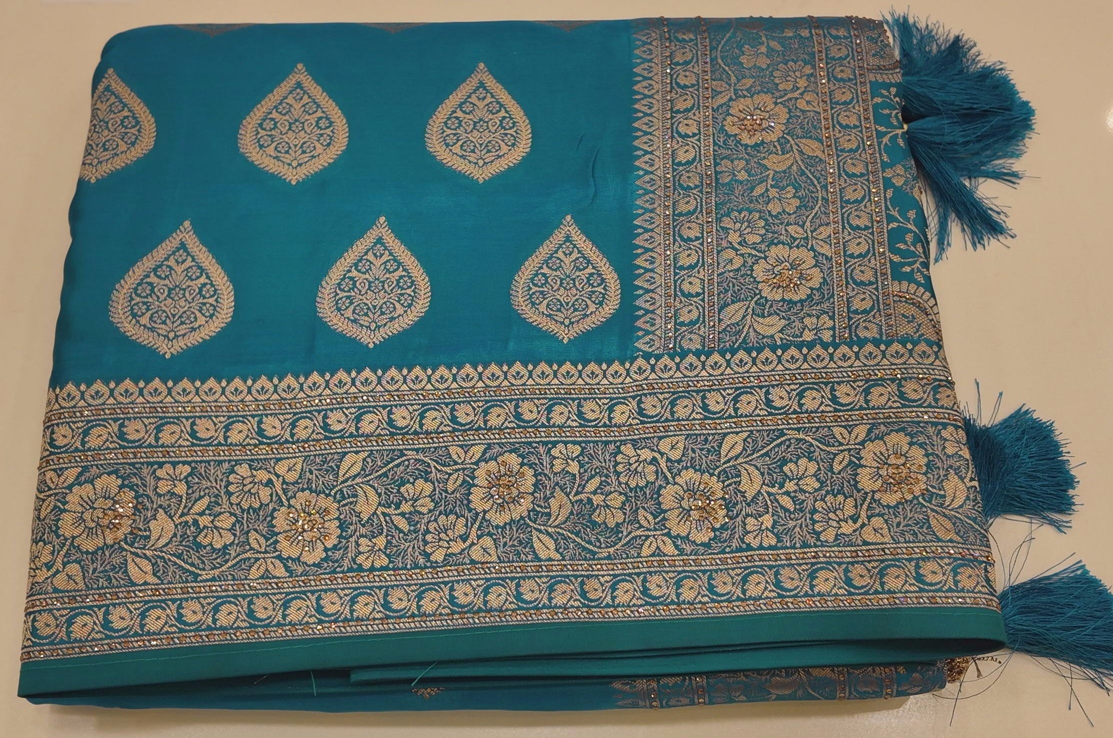 Peacock Charm: Vibrant Teal Saree with Gold Blossom Splendor",